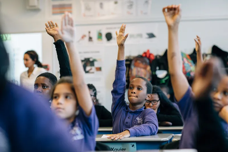 Students in a classroom raising their hands