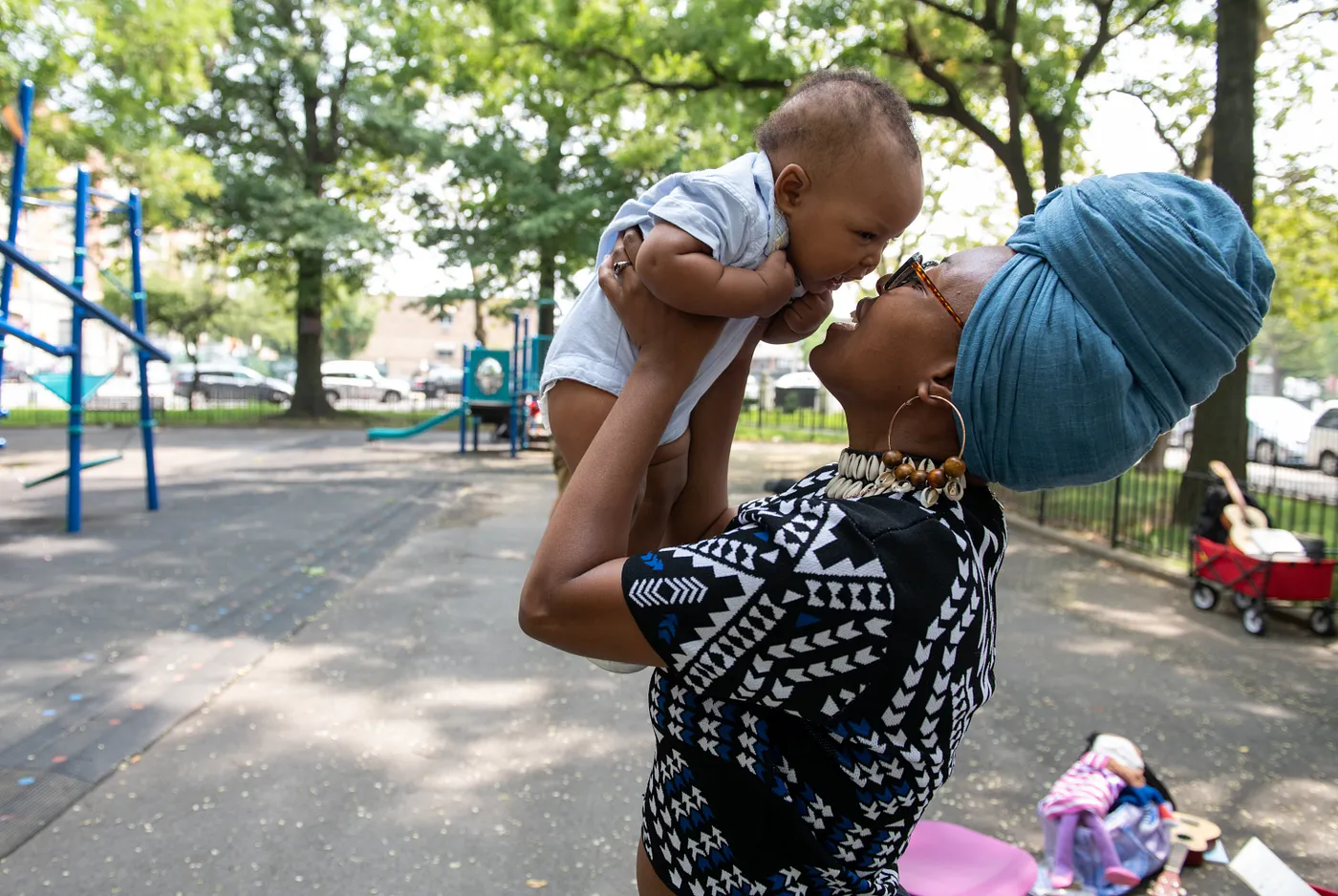 A woman holds up her infant in a Brooklyn park