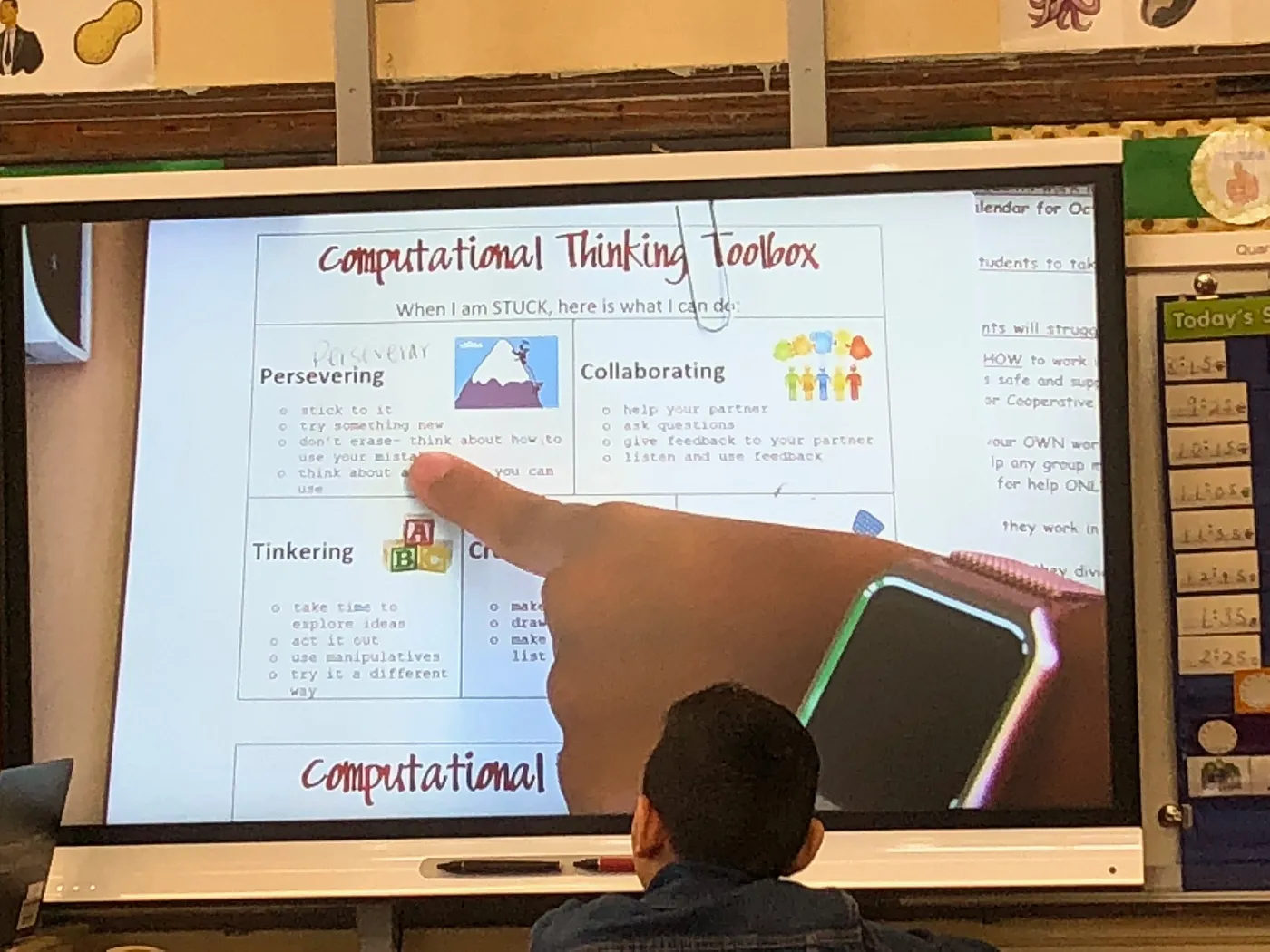 A student learning in front of a large screen in a classroom