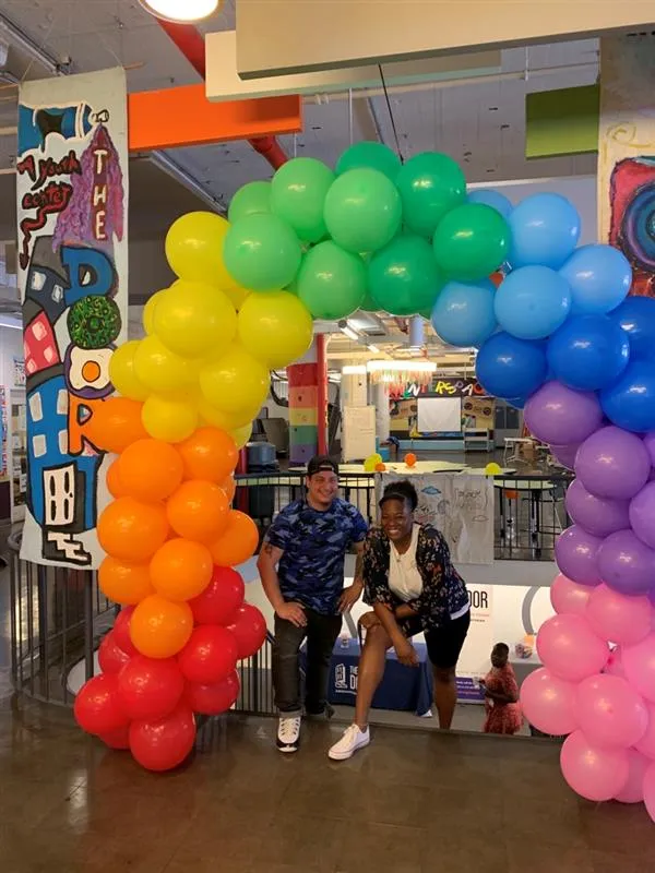 People pose under a rainbow balloon arch for Pride