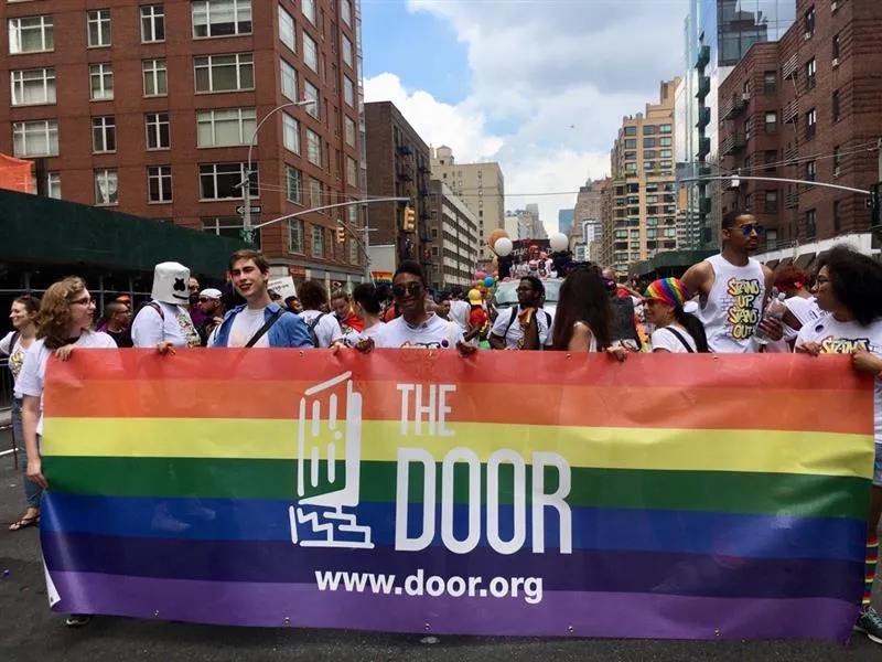 People march in the streets of New York for Pride carrying a banner for door.org.