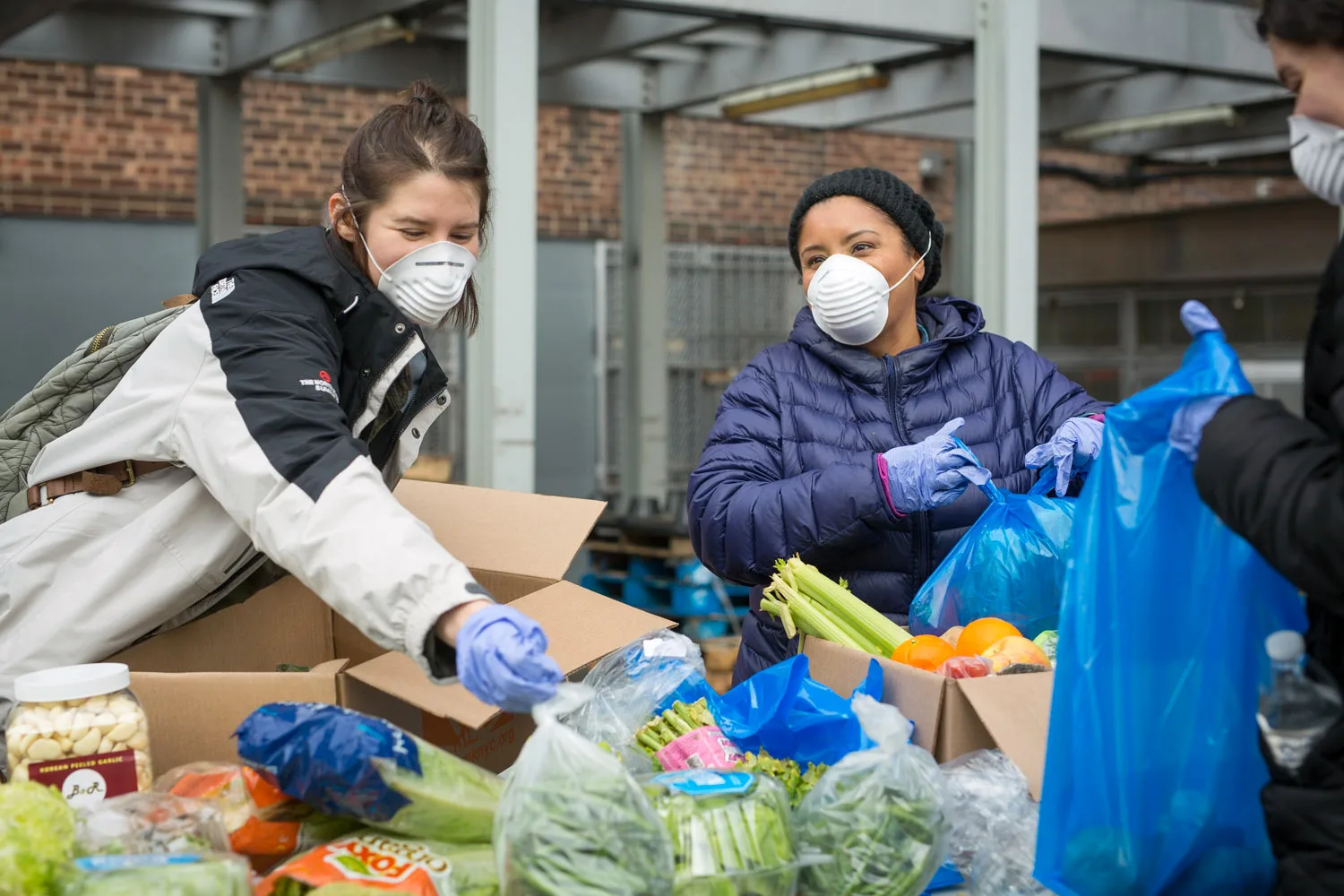 Two people volunteering to package emergency food and resources in an outdoor distribution setting.
