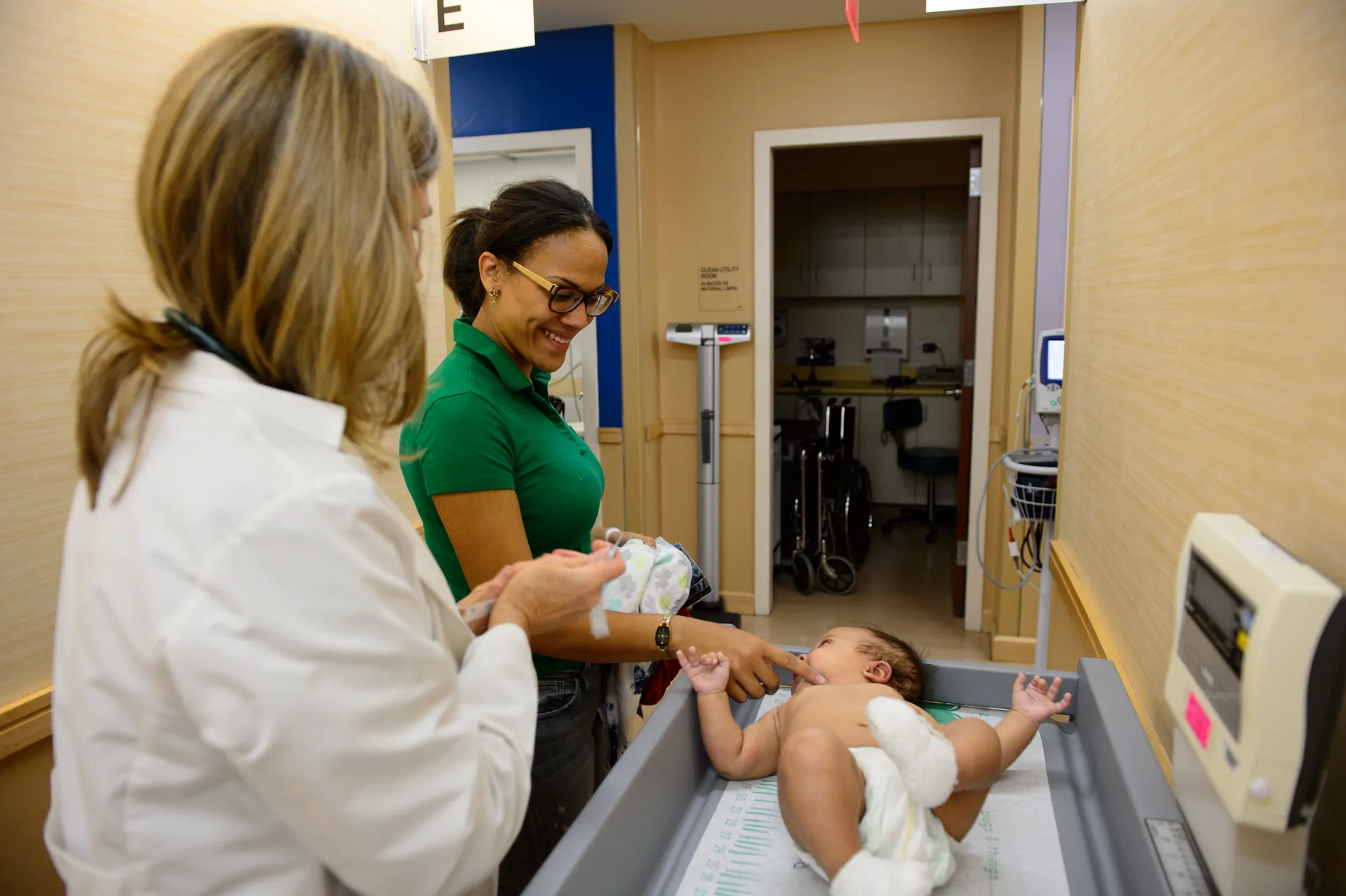 Two health professionals examining an infant in a hospital setting.