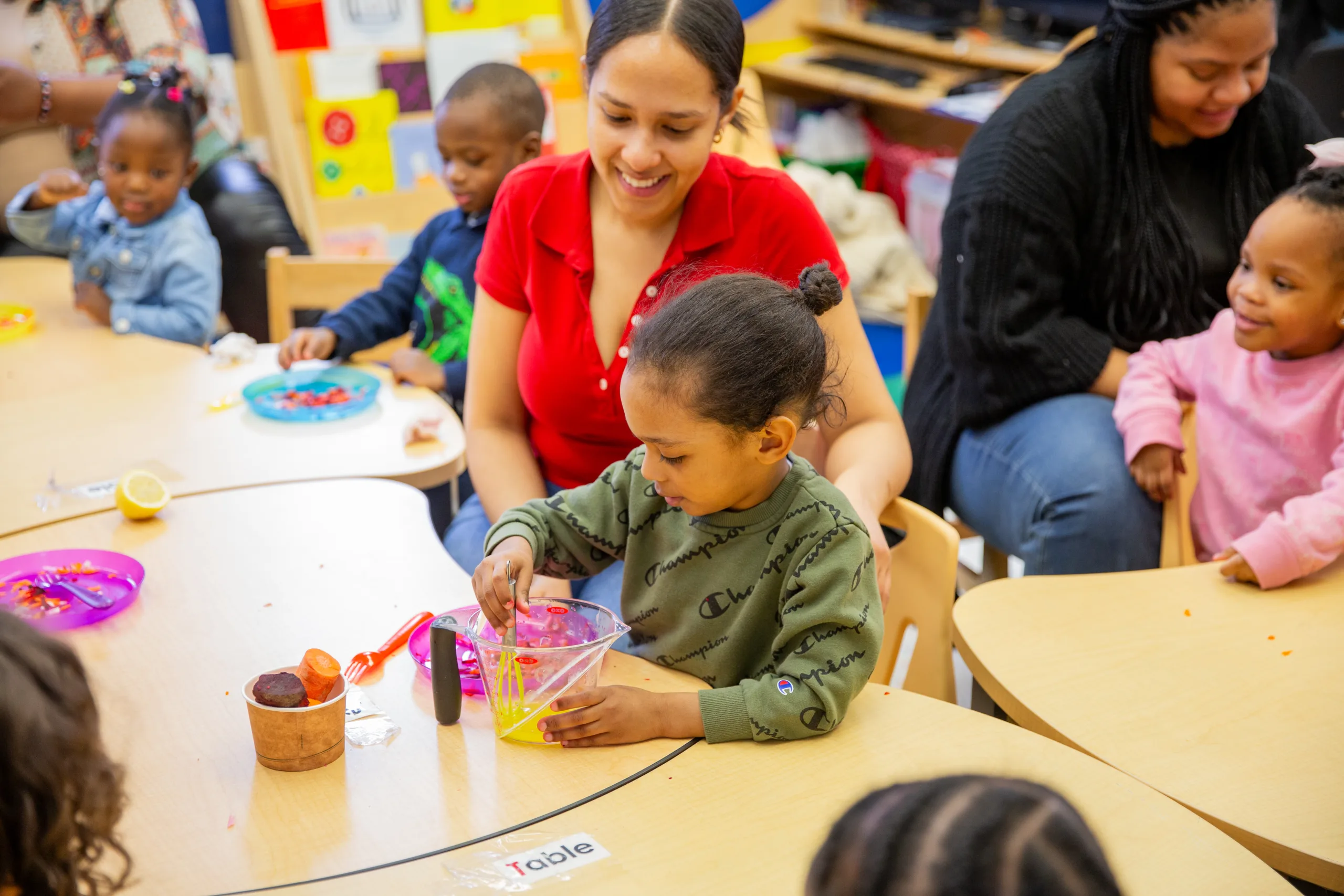 A child care provider helps a young child in an early learning classroom environment.